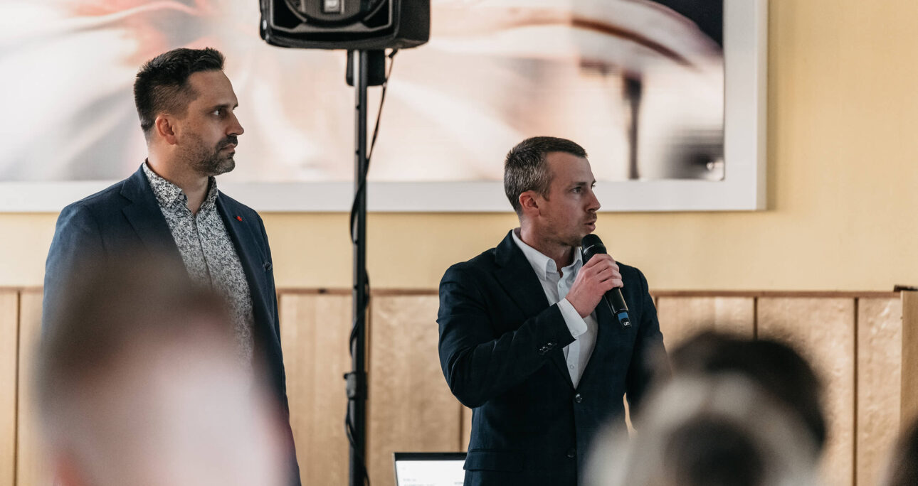 Muži mluví na prezentaci.